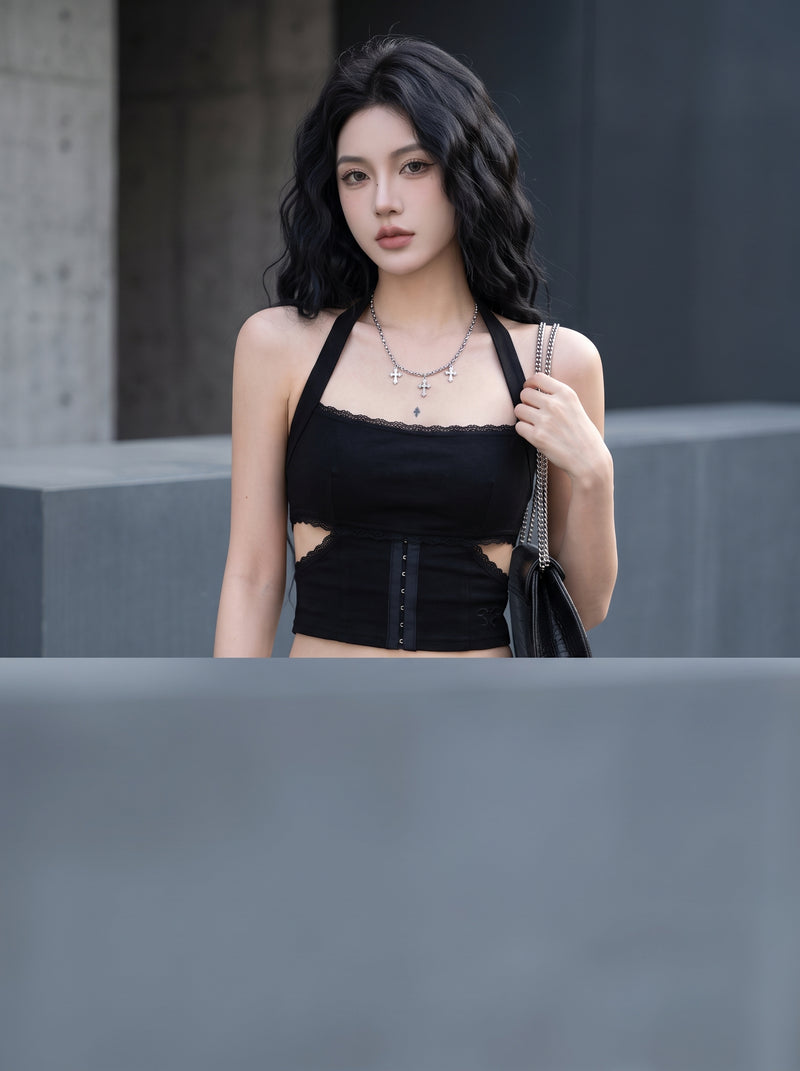 A woman posing in a halter cutout crop top against a soft-focus, minimalist architectural background with neutral gray tones.